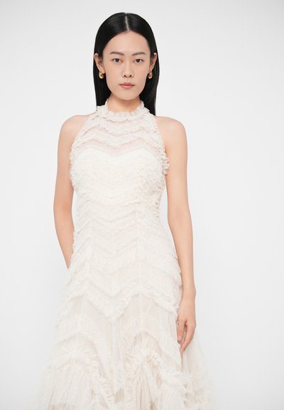 Biele šaty s golierom na krk, ozdobené vrstvami textúrovaných volánikov v chevronovom vzore, s priliehavou pásovou častou a prúdiacou sukňou.