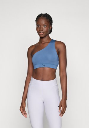 Blue one-shoulder sports bra with a fitted design, smooth texture, and logo accent; paired with light purple high-waisted leggings.