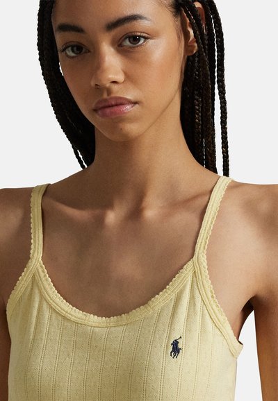 Yellow ribbed tank top with a scalloped neckline and adjustable straps, featuring a small navy logo on the left side.