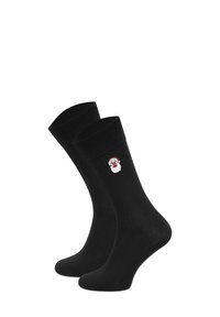 Czarne skarpetki z prążkowanym mankietem i haftowanym wzorem twarzy Świętego Mikołaja w kolorach czerwonym i białym. Gładka faktura i długość do połowy łydki.