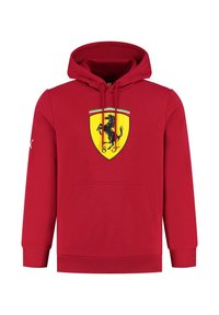 Czerwona bluza z kapturem wykonana z materiału o gładkiej fakturze, z centralnym czarnym logo Ferrari na żółtej tarczy, z kieszenią z przodu i sznurkami do ściągania.