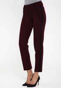 Pantalon taillé bourgogne avec des rayures noires sur les côtés, doté d'une texture lisse, d'une coupe slim et de poches avant inclinées.