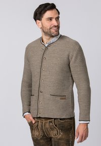 Hellbrauner Strickcardigan mit rundem Kragen, braunen Knöpfen und zwei vorderen Taschen. Akzentuiert mit dunklen Abschlüssen und einem Markenetikett.