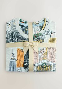 Folded t-shirt featuring a New York skyline design, made of light gray fabric, tied with a gold ribbon, detailed with holiday accents.
