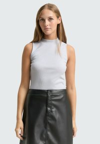 Lichtgrijze mouwloze top met een hoge halslijn, gecombineerd met een zwarte faux leren rok met knoopsluiting en een gladde textuur.