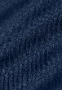 Close-up van een getextureerde marineblauwe gebreide stof met zichtbare steken en subtiele plooien.