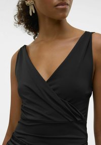 Top avvolgente nero realizzato in tessuto liscio, con scollatura a V profonda e vita arricciata per una silhouette aderente.