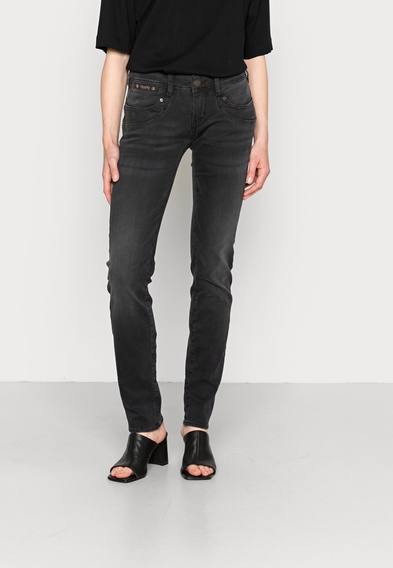 Svarta slim fit-jeans i denim med en medelhög midja, fem fickor och subtila blekningar. Kombineras med svarta mules med blockklack och öppen tå.