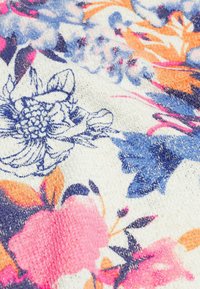 Stof met bloemenpatroon in het wit, met roze, blauwe en oranje bloemen. De textuur lijkt zacht en lichtjes gestructureerd.