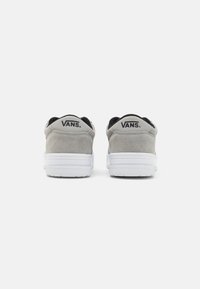 Grijze suède Vans-schoenen met zwarte accenten, witte rubberen zolen en een logo op de hak. Rond ontwerp met een gewatteerde kraag voor comfort.