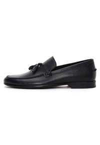 Black leather loafers featuring a textured finish, rounded toe, and decorative tassel detail on the vamp; low-profile rubber sole.