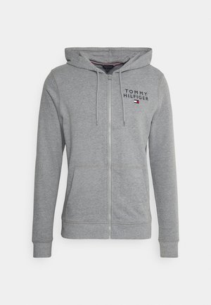 Grå zip-up hættetrøje lavet af bomuldsblanding. Har en foret hætte, frontlommer og "TOMMY HILFIGER" logo med en lille flagdetalje.