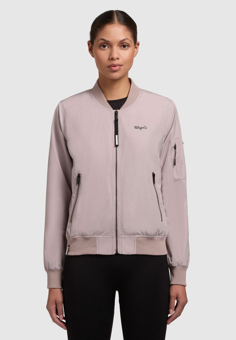 Heleda roosa bomber-jakk ribbed cuffs ja hemiga, lukuga taskud ja vasaku käe tasku. Sile tekstuur ja juhuslik sobivus.
