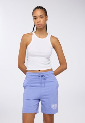 Canottiera bianca a coste abbinata a pantaloni corti in cotone azzurri chiari, con cintura elastica e grafica "NEW YORK" in bianco.