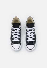 Pair of black canvas high-top sneakers with white laces, rubber toe caps, and white soles viewed from above on white background.