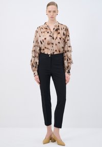Beige blouse with black leopard spots, ruffled sleeves, and button closure. Black tapered pants with a gold button. Yellow block-heeled shoes.
