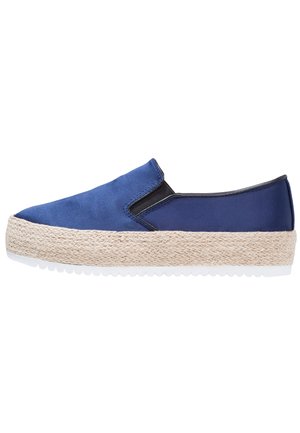 Blå slip-on sko lavet af blødt stof med en naturlig tov-mellemsål og hvid gummi-ydersål, med elastiske sider for nem påtagning.