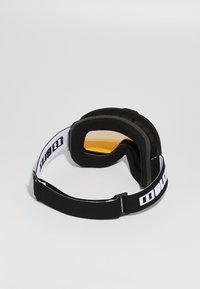Black ski goggles with yellow tinted lens, soft foam padding, adjustable black strap featuring white logo, designed for comfort and visibility.