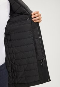 Schwarze Jacke mit gestepptem Innenfutter und Reißverschlusstasche, ausgestattet mit einer glatten Außenstoff und Reißverschluss-Verschlüssen.