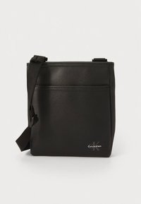 Czarna torebka na ramię wykonana z gładkiego materiału syntetycznego, o prostokątnym kształcie, z regulowanym paskiem i przednią kieszenią z subtelnym logo.