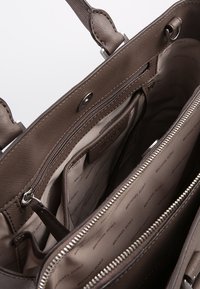 Bruine synthetische handtas met een ritssluiting en meerdere compartimenten. Gevoerd met een logo-patroon stof voor een georganiseerde opbergruimte.