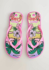 Poros rožinių šlepečių su tropiniais gėlėtai ir palmės medžio raštais bei „Cherry Coke“ tekstu pado pusėje.