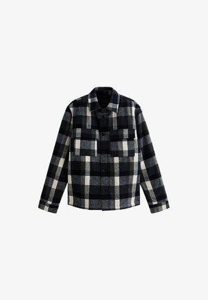 Camisa de cuadro en negro, blanco y gris, de manga larga con botones, con dos bolsillos en el pecho y un cuello, exhibida sobre un fondo blanco.