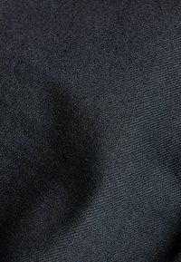 Černá tkanina s jemnou strukturou, která zobrazuje detailní pohled na povrch materiálu a subtilní variace v odstínech.