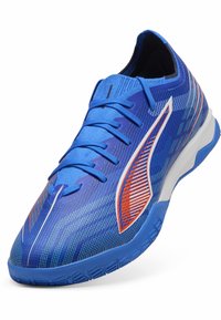 Blaue Sportschuhe mit einer Strick-Oberfläche, Schnürverschluss, dynamischem Streifen in Weiß und Orange sowie einer strukturierten Gummisohle für Halt.