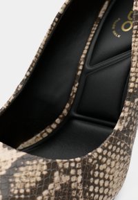 Escarpin à bout pointu imprimé serpent, présentant une surface extérieure synthétique texturée marron et crème ainsi qu'une doublure intérieure noire rembourrée. Design élégant.