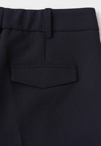 Tissu de pantalon bleu marine à texture lisse, doté d'une poche à rabat arrière et d'une ceinture droite, conçu pour le confort et la polyvalence.
