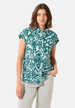 Camicia a maniche corte con bottoni in teal con un motivo astratto bianco. Tessuto leggero con una vestibilità rilassata, dotata di colletto a punta e maniche arrotolate.