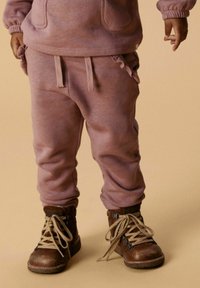 Gaiši rozā sporta bikses ar brīvu piegriezumu, ar saņemtā jostasvītnes un sānu kabatām, apvienotas ar brūniem zamšādas zābakiem ar auklēm.