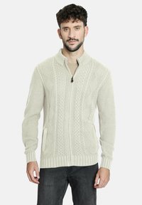 Suéter ligero color beige claro con textura de punto trenzado, puños y dobladillo acanalados, y dos bolsillos frontales. Apropiado para uso casual.