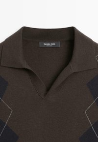 Polo marrone lavorata a maglia con scollo a V, caratterizzata da motivi a diamante blu scuro e cuciture bianche sottili. L'etichetta reca la scritta "Massimo Dutti".