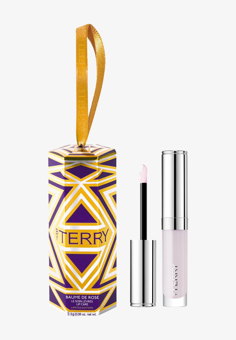 Baume à lèvres dans une boîte géométrique violette et dorée avec un ruban jaune ; comprend un tube transparent avec un applicateur noir et une wand à pointe rose.