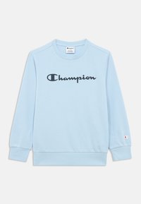 Ανοιχτό μπλε φούτερ με μακριά μανίκια και στρογγυλή λαιμόκοψη. Φέρει το λογότυπο "Champion" σε μαύρο χρώμα πάνω στο στήθος και ένα μικρό λογότυπο στην μανσέτα.