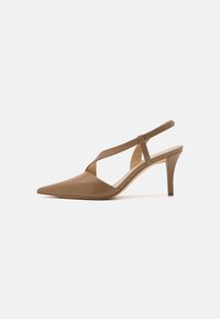 Escarpins à bout pointu en cuir tan avec un design à découpes courbées et un talon aiguille de hauteur moyenne. Texture lisse avec des accents minimaux.