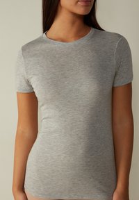 Grå t-shirt med kort ärm gjord av mjukt, lätt tyg. Enkel rund halsringning och smal passform med en slät textur.