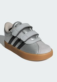 Sivé syntetické kožené tenisky s dvoma suchými zipsami, tromi čiernymi pruhmi na boku, sivou gumovou podrážkou a textúrovanými detailmi.