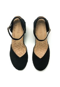 Calzature in suede nero con punta arrotondata, cinturino regolabile alla caviglia e soletta testurizzata con motivo a foglia. Materiale morbido con tacco basso.