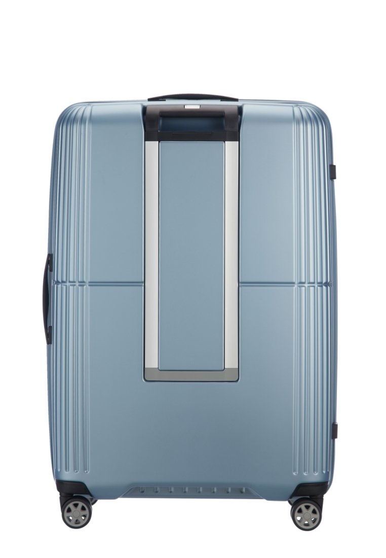 Valise rigide bleue avec des rainures verticales, une poignée encastrée et quatre roues pivotantes pour plus de mobilité. Présente un panneau d'accent en argent.
