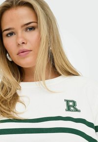 Sweatshirt blanc avec des rayures horizontales vertes et un logo 'R' brodé en haut à gauche. Tissu doux et col rond.