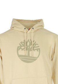 Felpa beige con cappuccio e lacci, con un grande logo stilizzato di un albero stampato al centro davanti.