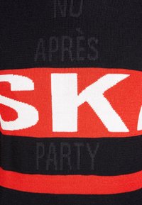 Schwarzer Strickpullover mit auffälligen roten und weißen Streifen sowie dem Text "SKI" und "APRES PARTY" in kontrastierenden Farben. Weicher Stoff.