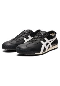 Mustat nahkaiset tennarit, joissa on valkoiset raidat, pyöreä kärki, nauhoilla varustettu malli, teksturoitu kumipohja ja huomaamattomat brändäysdetailit.