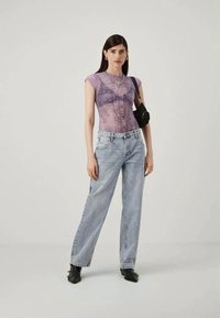 Violetiniu džinsiniu marškinėliais trumpomis rankovėmis, su mygtukų užsegimu ir puošmenomis, derinami su šviesiai mėlynomis plačiomis kelnėmis ir juodais aulinukais.