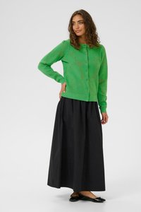 Cardigan verde cu model tricotat, închidere cu nasturi și mâneci lungi, asociat cu o fustă maxi neagră și balerini negri. Material texturat.