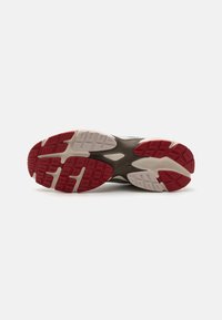 Athletic shoe outsole featuring a red and white rubber design with textured patterns and grooves for traction.