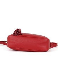 Rød lædertaske med en struktureret overflade, flad form og en dekorativ frynse på toppen. Har en tynd justerbar rem.